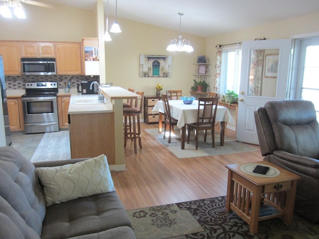 2220 Alpine Dr, Helena, MT 59601 - living area featuring vaulted ceiling, a chandelier, light wood-style flooring, and healthy amount of natural light