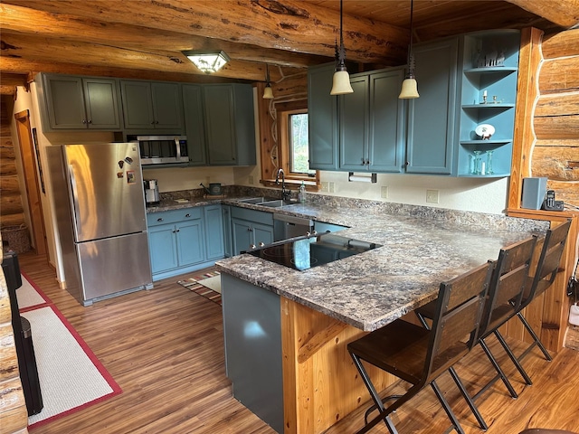 3966 Main Boulder Rd, Big Timber, MT 59011 - kitchen featuring stainless steel appliances, rustic walls, a sink, wood finished floors, and a peninsula