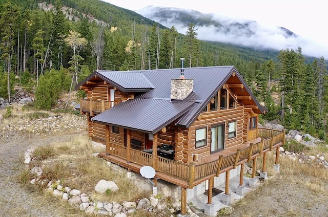 3966 Main Boulder Rd, Big Timber, MT 59011 - rear view of house with a view of trees, log exterior, metal roof, a chimney, and a deck with mountain view