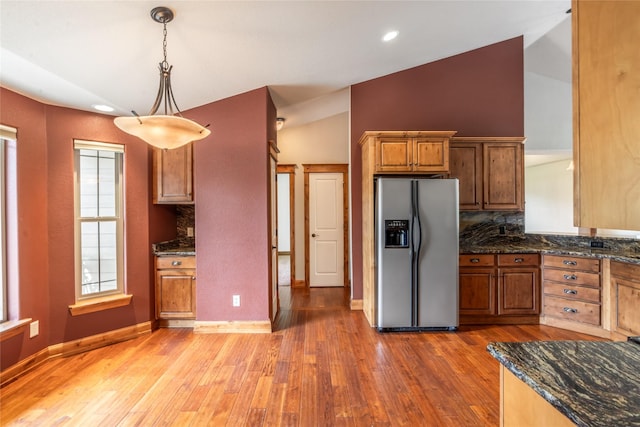 10 Canyon Breeze Ct, Stevensville, MT 59870 - kitchen featuring stainless steel refrigerator with ice dispenser, brown cabinets, light wood-type flooring, vaulted ceiling, and hanging light fixtures