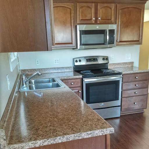 1380 Easy St, Billings, MT 59105 - kitchen with stainless steel appliances, a sink, brown cabinets, and dark wood-style floors