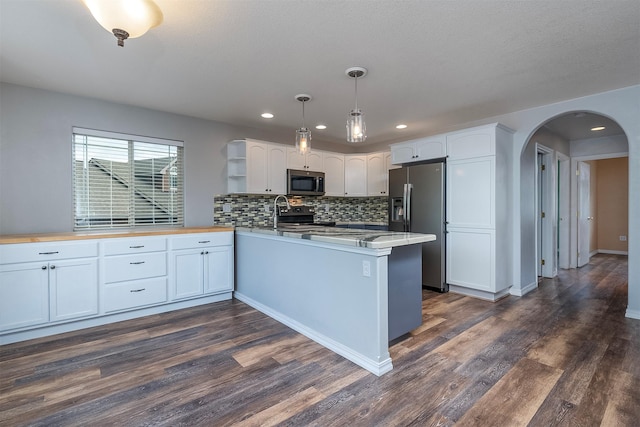 1605 Lund Ln, Polson, MT 59860 - kitchen with appliances with stainless steel finishes, a peninsula, arched walkways, open shelves, and tasteful backsplash