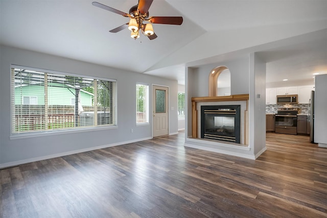 1605 Lund Ln, Polson, MT 59860 - unfurnished living room featuring vaulted ceiling, ceiling fan, a multi sided fireplace, dark wood-style floors, and baseboards