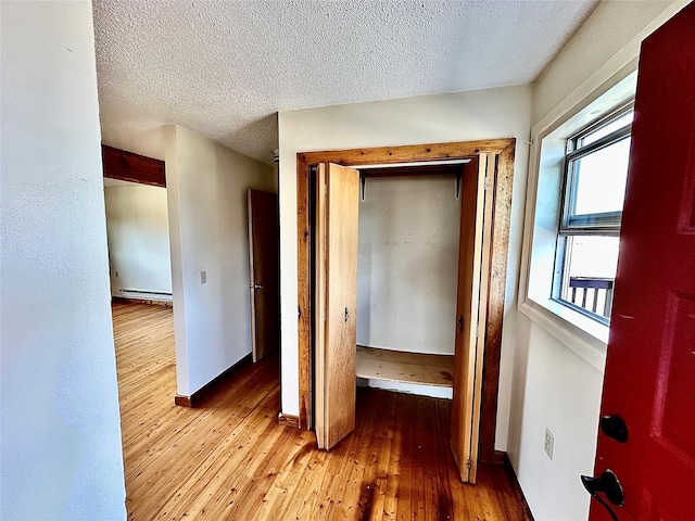 310 W Armitage St, Ennis, MT 59729 - hall with light wood-type flooring, baseboard heating, baseboards, and a textured ceiling