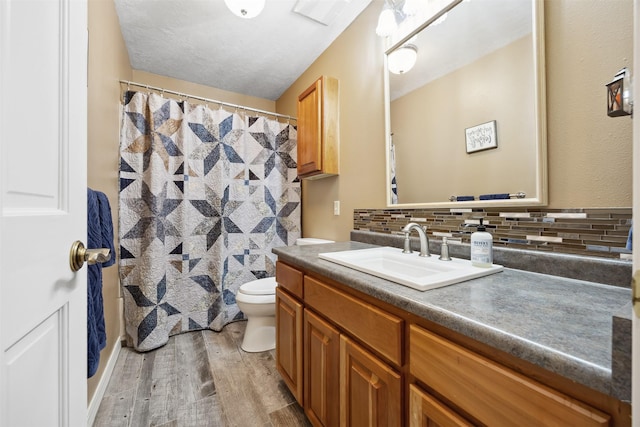 150 Painted Mdws, Butte, MT 59701 - full bathroom with vanity, wood finished floors, toilet, decorative backsplash, and a shower with shower curtain