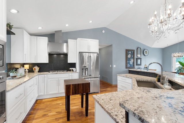 5634 Fairview Ln, Florence, MT 59833 - kitchen featuring stainless steel fridge, wall chimney exhaust hood, a chandelier, a sink, and vaulted ceiling