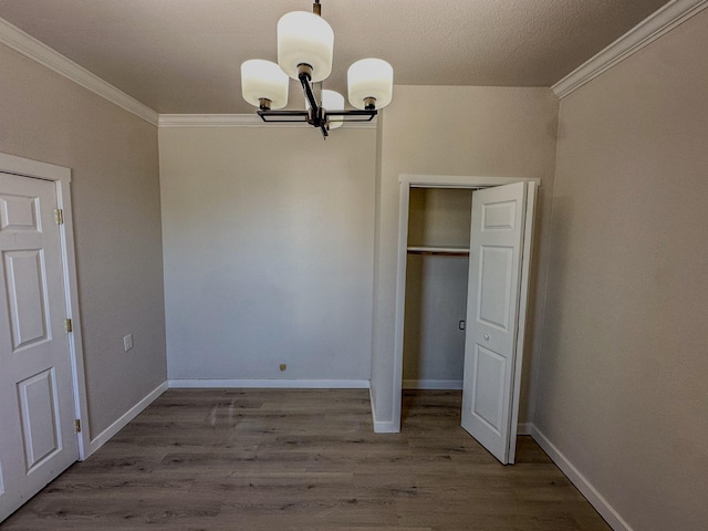 211 W Main St, East Helena, MT 59635 - unfurnished bedroom with ornamental molding, a chandelier, wood finished floors, baseboards, and a closet