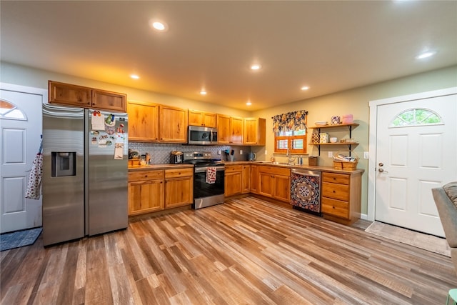 1118 Dakota Ave, Libby, MT 59923 - kitchen featuring appliances with stainless steel finishes, a sink, light wood-type flooring, open shelves, and decorative backsplash