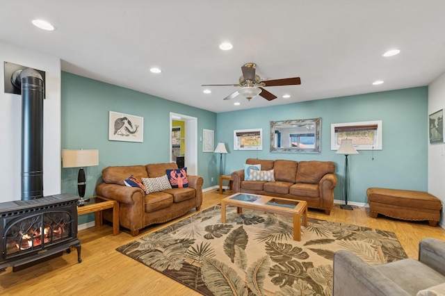 33604 Whitecap Ln, Bigfork, MT 59911 - living room featuring a wood stove, a ceiling fan, recessed lighting, baseboards, and wood finished floors