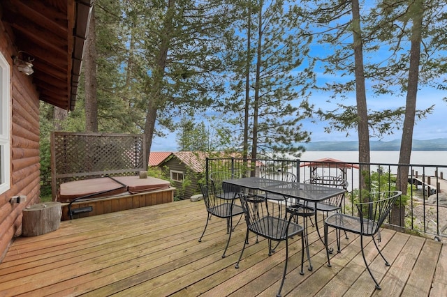 33604 Whitecap Ln, Bigfork, MT 59911 - wooden terrace featuring a covered hot tub, a water view, and outdoor dining area