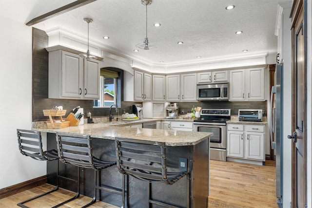 4884 Lower Miller Creek Rd, Missoula, MT 59803 - kitchen with stainless steel appliances, a peninsula, light wood finished floors, arched walkways, and a textured ceiling