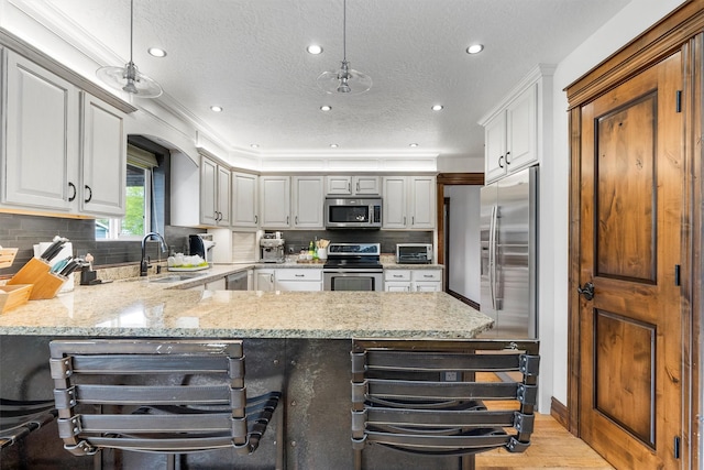 4884 Lower Miller Creek Rd, Missoula, MT 59803 - kitchen featuring appliances with stainless steel finishes, a peninsula, recessed lighting, light stone countertops, and a textured ceiling