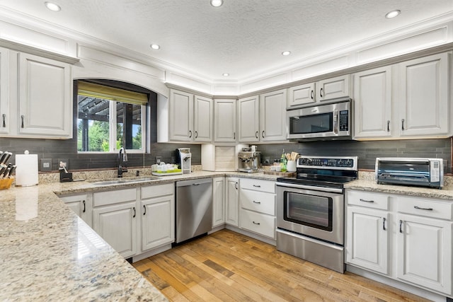 4884 Lower Miller Creek Rd, Missoula, MT 59803 - kitchen with stainless steel appliances, backsplash, light wood-style floors, a textured ceiling, and white cabinetry