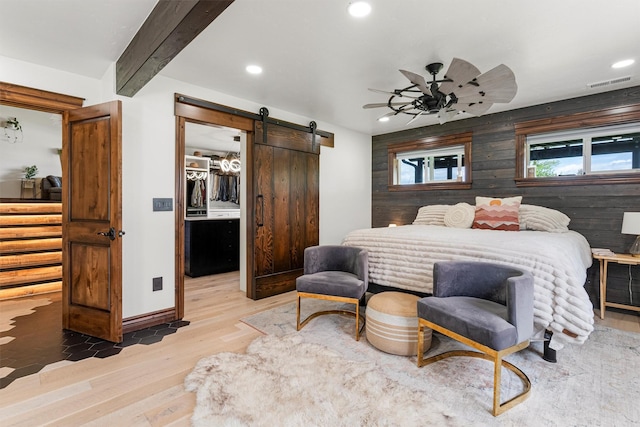 4884 Lower Miller Creek Rd, Missoula, MT 59803 - bedroom featuring a barn door, wood finished floors, a spacious closet, recessed lighting, and beam ceiling