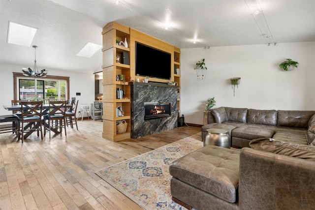 4884 Lower Miller Creek Rd, Missoula, MT 59803 - living room featuring light wood finished floors, a skylight, a high end fireplace, and a chandelier