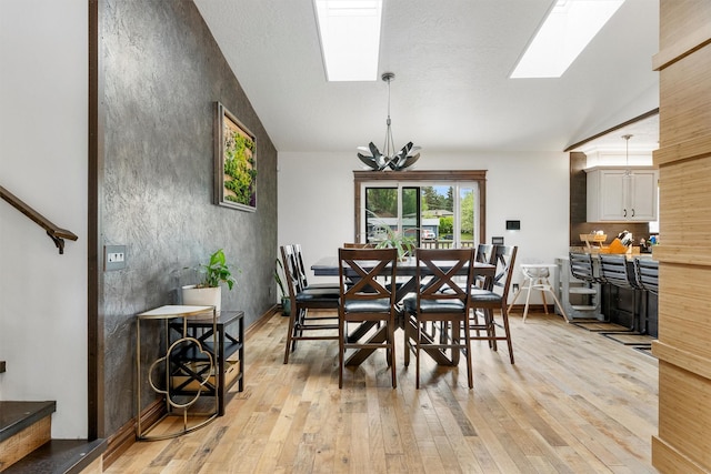 4884 Lower Miller Creek Rd, Missoula, MT 59803 - dining room featuring vaulted ceiling, a skylight, light wood finished floors, and a chandelier