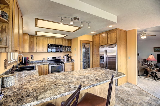 31521 Mcdonald Lake Rd, Saint Ignatius, MT 59865 - kitchen featuring appliances with stainless steel finishes, a sink, a peninsula, a textured ceiling, and a ceiling fan