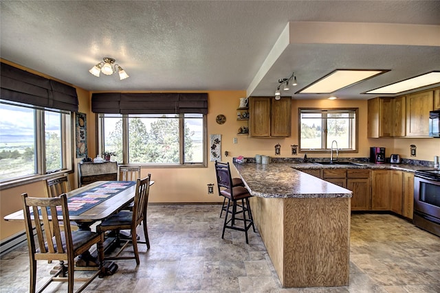 31521 Mcdonald Lake Rd, Saint Ignatius, MT 59865 - kitchen with a peninsula, stainless steel electric stove, a sink, brown cabinetry, and a breakfast bar