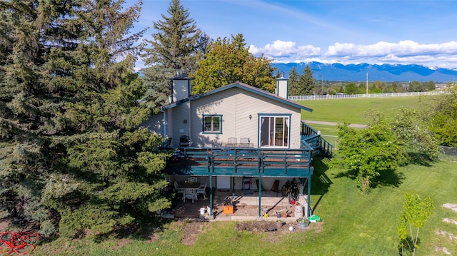 280 Hartt Hill Dr, Kalispell, MT 59901 - back of property with a chimney, a patio, a deck with mountain view, and a yard