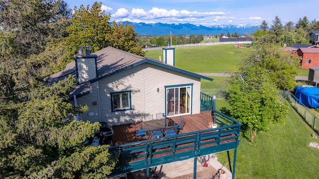 280 Hartt Hill Dr, Kalispell, MT 59901 - back of property with a chimney, a yard, and a deck with mountain view
