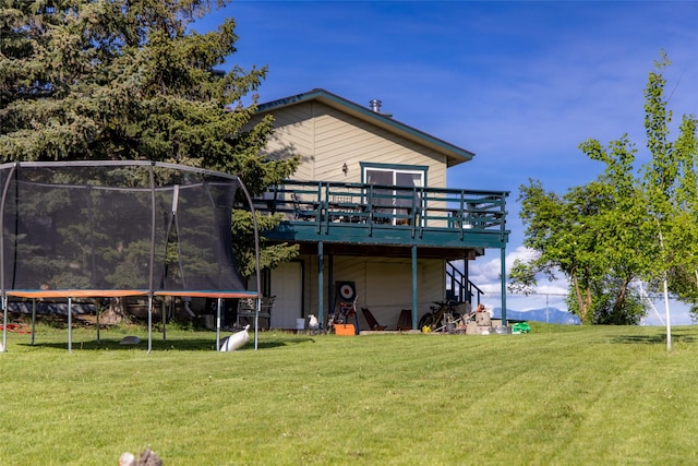 280 Hartt Hill Dr, Kalispell, MT 59901 - back of property featuring a trampoline, a yard, and a deck