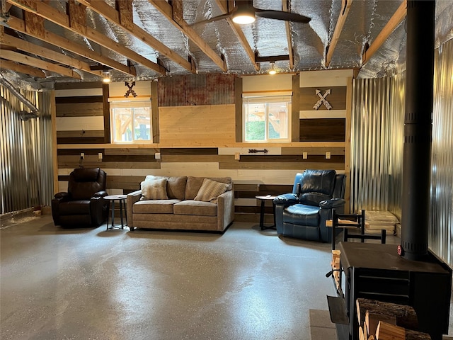 14367 US Highway 2 E, Essex, MT 59916 - living area featuring wooden walls, a ceiling fan, a wood stove, and finished concrete floors