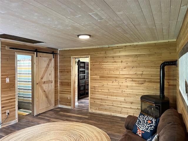 14367 US Highway 2 E, Essex, MT 59916 - living area featuring wooden walls, a wood stove, a barn door, dark wood finished floors, and wooden ceiling