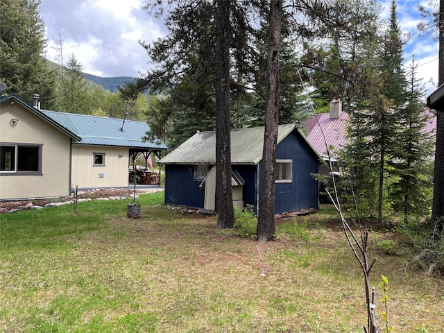 14367 US Highway 2 E, Essex, MT 59916 - back of property with metal roof, a yard, an outbuilding, and a mountain view