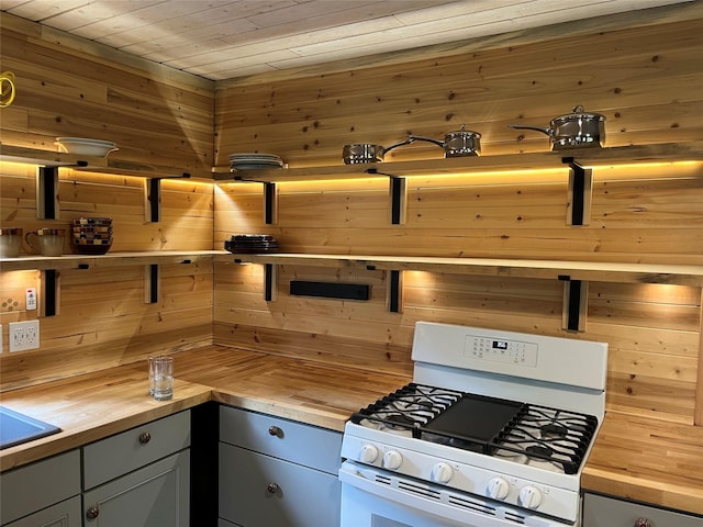 14367 US Highway 2 E, Essex, MT 59916 - kitchen featuring butcher block countertops, white range with gas stovetop, gray cabinets, wooden walls, and wood ceiling