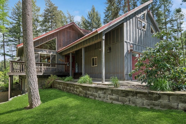 14132 Pine St, Bigfork, MT 59911 - view of front facade with board and batten siding, a front lawn, and a deck
