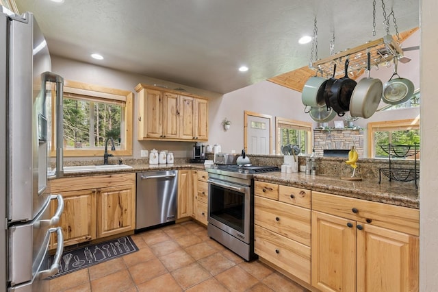 14132 Pine St, Bigfork, MT 59911 - kitchen with stainless steel appliances, light brown cabinetry, recessed lighting, a sink, and a stone fireplace