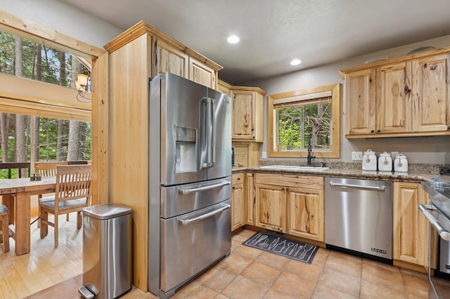 14132 Pine St, Bigfork, MT 59911 - kitchen with stainless steel appliances, a sink, light brown cabinets, recessed lighting, and stone counters