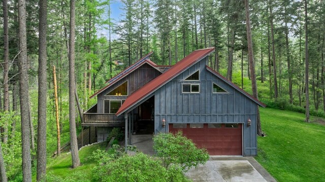 14132 Pine St, Bigfork, MT 59911 - chalet / cabin with a wooded view, a front yard, driveway, board and batten siding, and a wooden deck