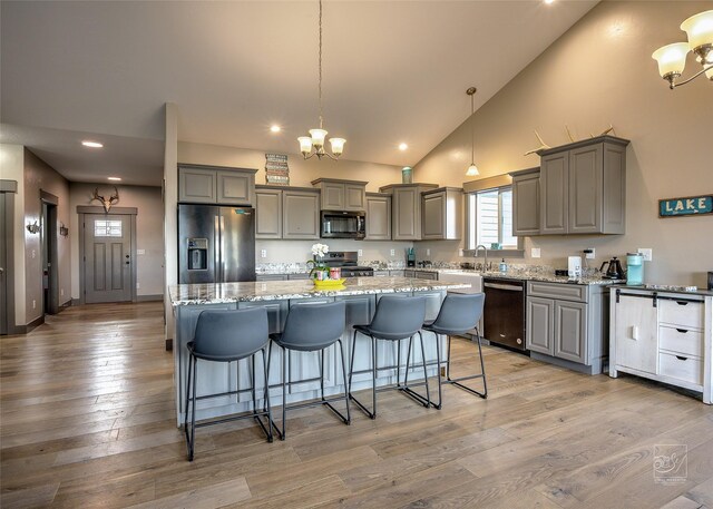 4731 Sea Ray Rd, Helena, MT 59602 - kitchen featuring appliances with stainless steel finishes, gray cabinetry, a chandelier, light stone countertops, and light wood-style flooring