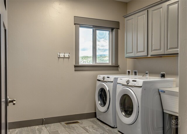 4731 Sea Ray Rd, Helena, MT 59602 - laundry room featuring washer and clothes dryer, cabinet space, baseboards, and light marble finish floors