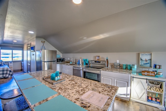 4731 Sea Ray Rd, Helena, MT 59602 - kitchen with appliances with stainless steel finishes, vaulted ceiling, hardwood / wood-style flooring, a sink, and white cabinetry