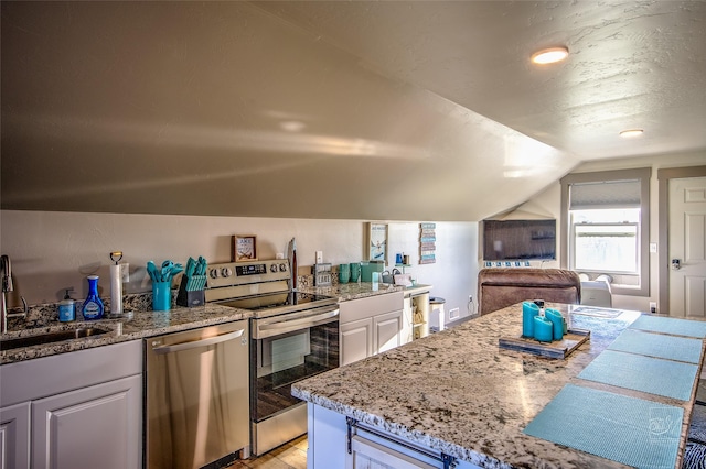 4731 Sea Ray Rd, Helena, MT 59602 - kitchen featuring appliances with stainless steel finishes, a sink, light stone counters, lofted ceiling, and light wood finished floors