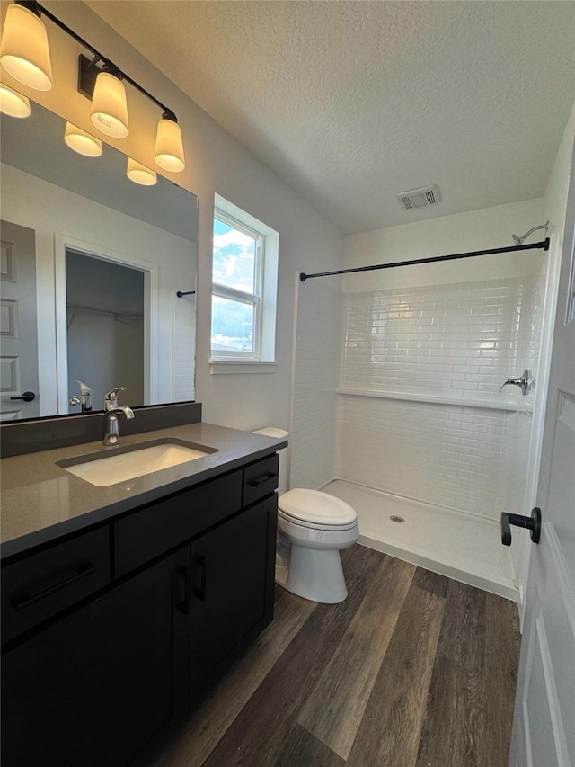2283 Depot Way, Missoula, MT 59808 - bathroom with wood finished floors, vanity, a tile shower, toilet, and a textured ceiling