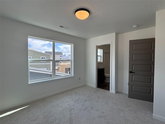 2283 Depot Way, Missoula, MT 59808 - unfurnished bedroom featuring carpet, a textured ceiling, baseboards, and connected bathroom