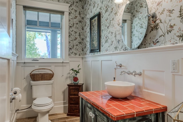 3070 River Lakes Dr, Whitefish, MT 59937 - bathroom with wallpapered walls, wainscoting, wood finished floors, toilet, and a decorative wall