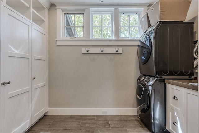 3070 River Lakes Dr, Whitefish, MT 59937 - laundry room featuring stacked washer / drying machine, cabinet space, baseboards, and healthy amount of natural light