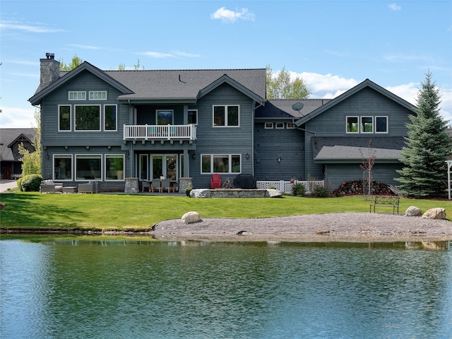 3070 River Lakes Dr, Whitefish, MT 59937 - rear view of house featuring a balcony, a water view, a lawn, and a chimney