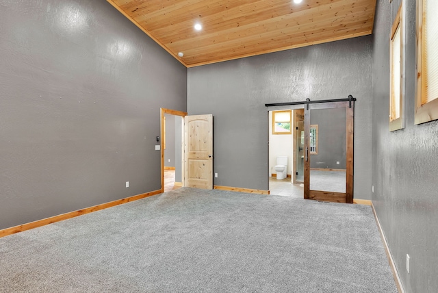 26 Two Rivers Rd, Saint Regis, MT 59866 - unfurnished bedroom featuring a barn door, wood ceiling, a high ceiling, baseboards, and carpet flooring