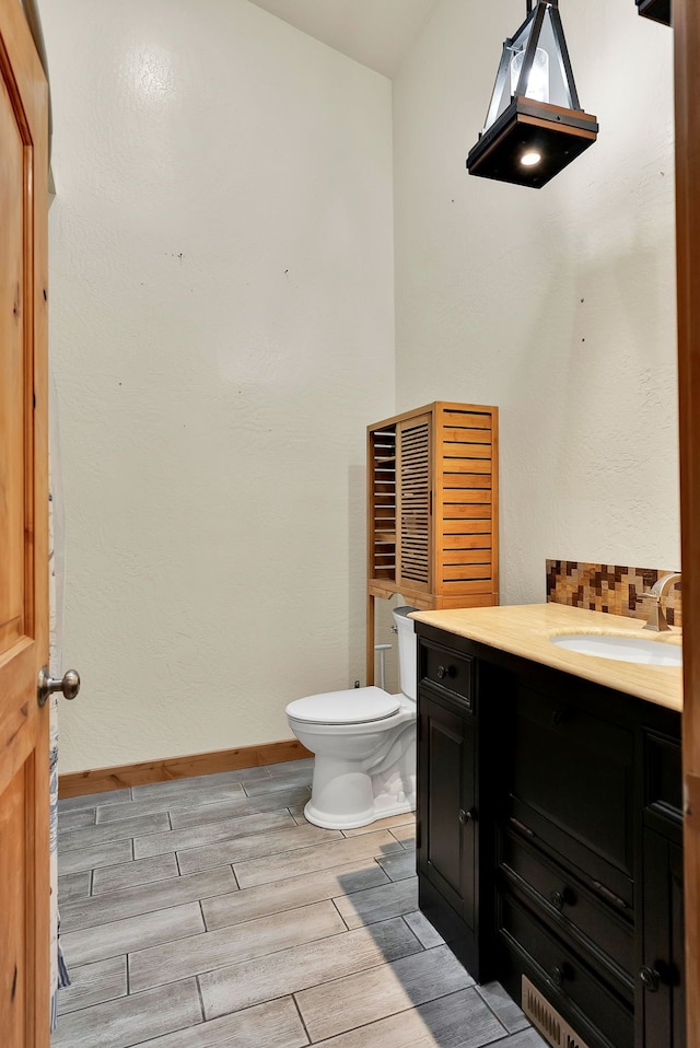 26 Two Rivers Rd, Saint Regis, MT 59866 - half bathroom with wood tiled floors, vanity, toilet, baseboards, and tasteful backsplash