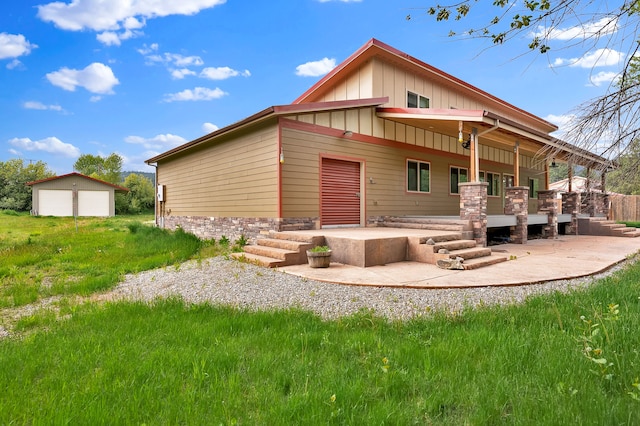 26 Two Rivers Rd, Saint Regis, MT 59866 - rear view of property with board and batten siding, a garage, a patio, an outbuilding, and stone siding