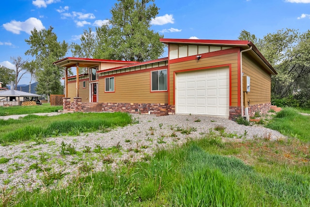 26 Two Rivers Rd, Saint Regis, MT 59866 - view of front facade with a garage, stone siding, and gravel driveway