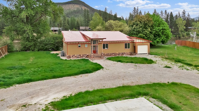 26 Two Rivers Rd, Saint Regis, MT 59866 - view of front facade with an attached garage, gravel driveway, a mountain view, metal roof, and central air condition unit