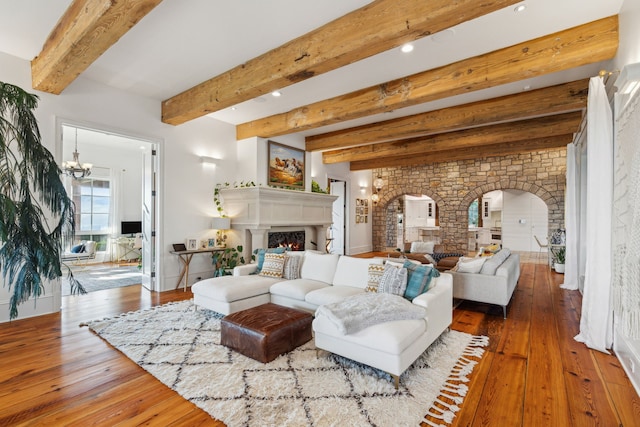 2761 Contour Rd, Missoula, MT 59802 - living area with arched walkways, a chandelier, hardwood / wood-style flooring, a warm lit fireplace, and beam ceiling