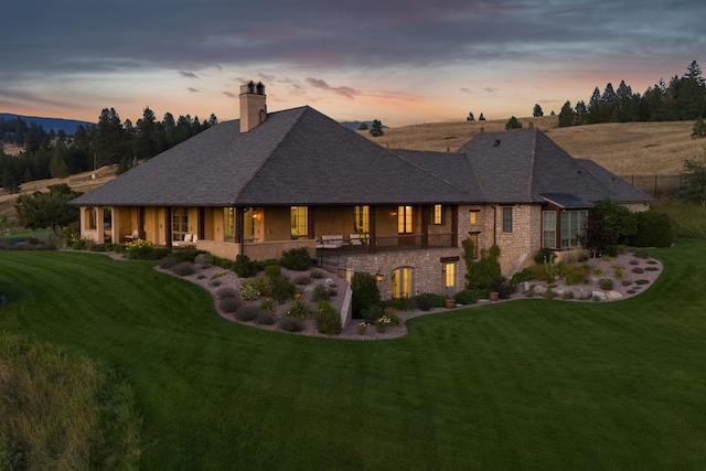 2761 Contour Rd, Missoula, MT 59802 - rear view of house featuring a yard, a chimney, stone siding, and a shingled roof