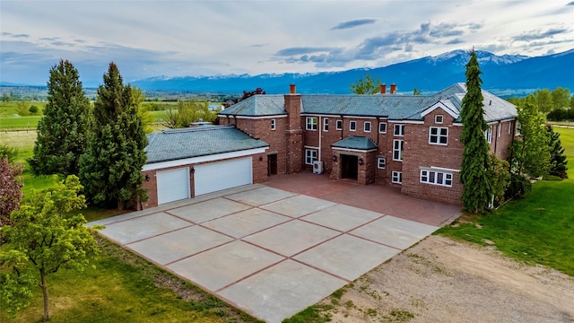 444 Windwalker Trl, Stevensville, MT 59870 - view of front of home with a mountain view, driveway, a chimney, brick siding, and a high end roof